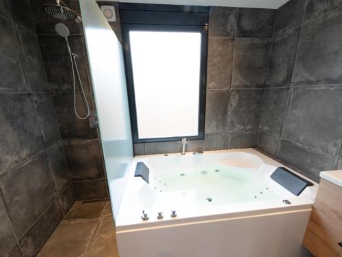 a bath tub in a bathroom with a window at Wellness Bungalow with whirlpool and sauna in Zevenhuizen