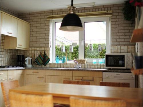 een keuken met een tafel, een magnetron en een raam bij Huijsmansverhuur Type A de Luxe Grevelingen 16 