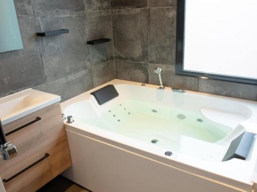 uma banheira branca na casa de banho com uma janela em Wellness Bungalow with whirlpool and sauna em Zevenhuizen
