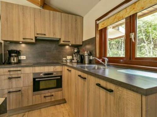 a kitchen with wooden cabinets and a large window at Huijsmansverhuur Type C Comfort Plus Prinsenhof 51 in Ouddorp