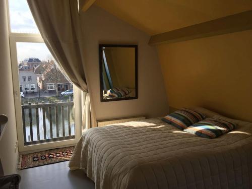 een slaapkamer met een bed en een groot raam bij Aan de Kade Modern retreat in Enkhuizen