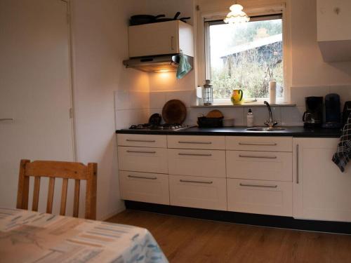 a kitchen with white cabinets and a sink and a window at Huijsmans Verhuur Type C Comfort Alexanderpark 201 in Ouddorp