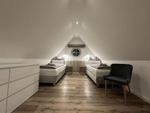 um quarto no sótão com 2 camas e uma cadeira em Eiderhuus Modern retreat em Tönning