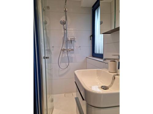 ein weißes Bad mit einer Dusche und einem Waschbecken in der Unterkunft The Blue House Modern retreat in Wangerooge