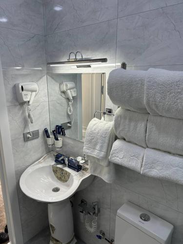 a bathroom with a sink and a pile of towels at Panorama Hotel & More in Samarkand