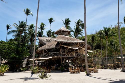 エルニドにあるDryft Darocotan Islandのヤシの木が茂る海岸の藁小屋