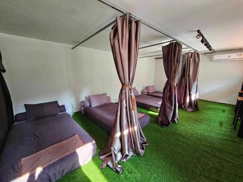 Zimmer mit 3 Betten und grünem Teppich in der Unterkunft Nahm Khao Sok in Khao Sok