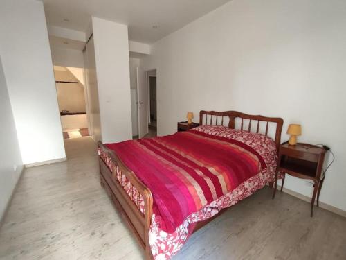 Schlafzimmer mit einem Bett mit einer roten Decke und einem Schreibtisch in der Unterkunft Très grand et bel appartement in Nîmes