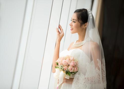 a bride is holding a bouquet of pink roses at Hotel Santika Premiere Hayam Wuruk Jakarta in Jakarta