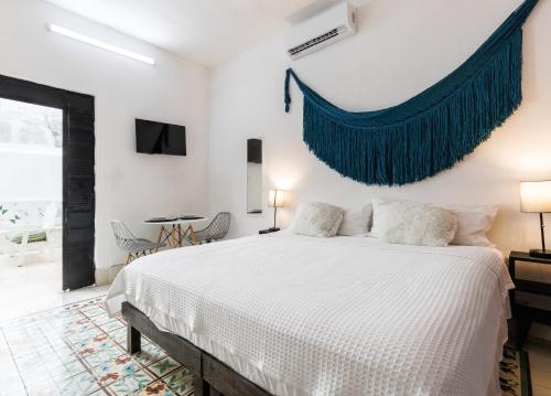 a bedroom with a white bed with a blue drape on the wall at CATEDRAL CENTRO DE MERIDA ESTUDIO2 in Mérida