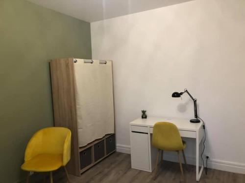Cette chambre comprend un bureau et deux chaises jaunes. dans l'établissement Pétillant cosy, à Reims
