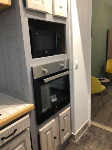 une cuisine avec un micro-ondes intégré et une télévision dans l'établissement Pétillant cosy, à Reims