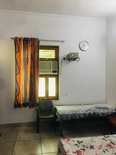 a room with two beds and a chair and a window at Anavrin home stay in Muzaffarnagar