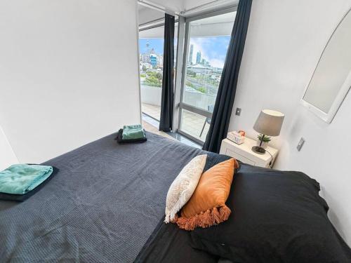 - une chambre avec un lit et une grande fenêtre dans l'établissement Le Mirage- Stylish, central apartment with pools, sauna, more, à Auckland