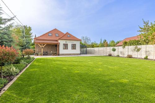 a yard with a house and a fence at Casa PERLA in Dunajská Streda