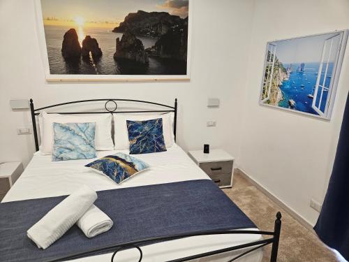 um quarto com uma cama com lençóis brancos e almofadas azuis em La Bomboniera em Capri