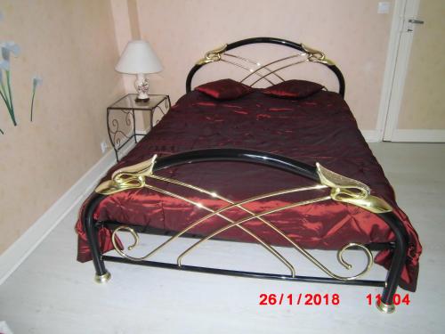 un lit avec une couette rouge et un cadre doré dans l'établissement Résidence des Bruyères, Mont Dore, à Mont-Dore