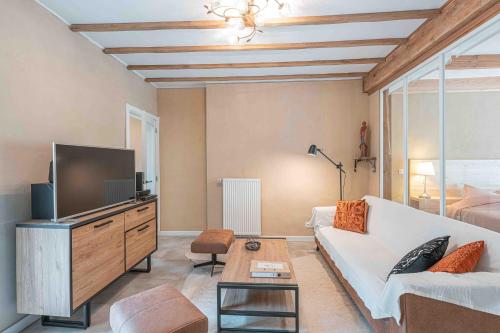 a living room with a white couch and a tv at Les Gites Kangourou Dinant in Dinant