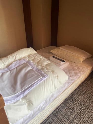 an unmade bed with a remote control on it at KOMOREBI HOSTEL-your cozy place- in Takayama