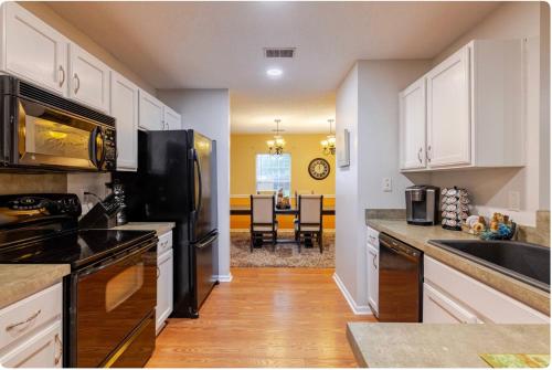 una cucina con armadietti bianchi e frigorifero nero di The Cozy Hidden Gem a Charleston