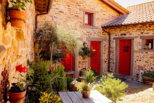 a stone house with red doors and plants at Via Avis in Santa Catalina de Somoza