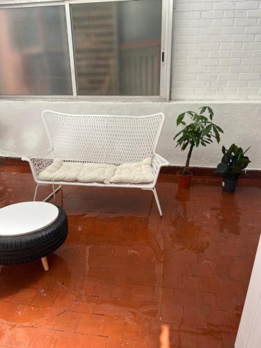 a white bench sitting on a porch with a plant at ONE PIECE Apartamento con patio in Alcobendas