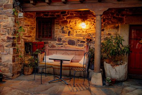 a table and chairs in front of a stone wall at Via Avis in Santa Catalina de Somoza