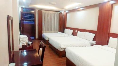 ein Hotelzimmer mit 2 Betten und einem Tisch in der Unterkunft Discovery Hotel in Sa Pa