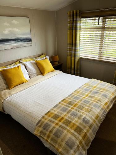 a bedroom with a large bed with yellow pillows at Sandy Bay Caravan Getaway in Newbiggin-by-the-Sea
