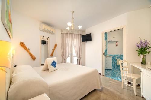 a white bedroom with a bed and a table at Albergo Diffuso Mannois in Orosei