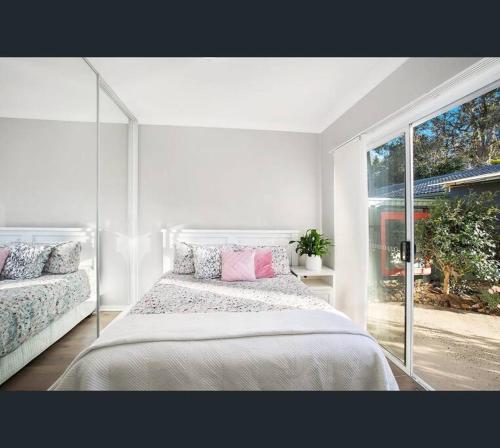 een witte slaapkamer met een bed en een groot raam bij Lake-view Retreat w Spa, nearby Beaches & Shopping in the Central Coast in Lakeside