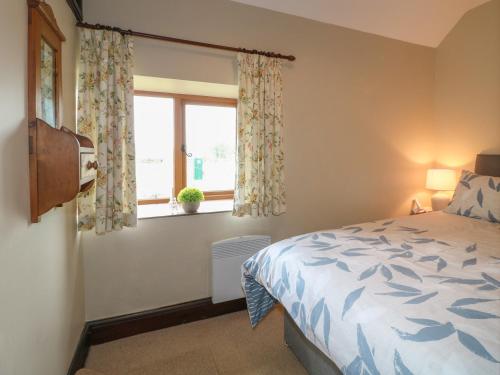 a bedroom with a bed and a window at Dove Cottage in Leek