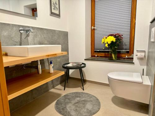 a bathroom with a sink and a toilet and a vase of flowers at Das besondere Moselhaus-Mosel ultranah Luxus Ferienhaus Mosel in Kinheim