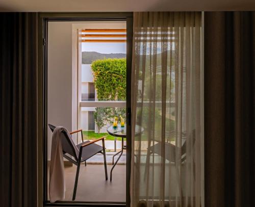 a sliding glass door to a balcony with a chair and a table at Samara Hotel Bodrum Ultra All Inclusive in Torba