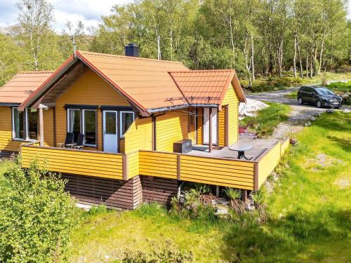 uma casa amarela com um deque num campo em 6 person holiday home in nneland em Ånneland