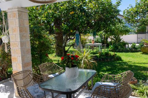 a patio table with chairs and a vase with flowers on it at Alex Studios & Apartments in Arillas