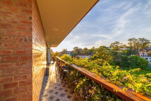 a balcony with a brick wall and flowers at Brick House Dalat Hotel in Da Lat