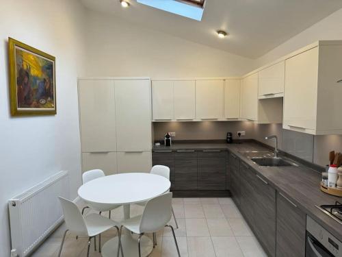 - une cuisine avec une table blanche et des chaises blanches dans l'établissement Weybridge garden cottage, à Weybridge