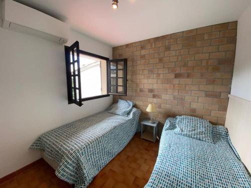 deux lits dans une chambre avec un mur de briques dans l'établissement Appartement t3 à 50m de la plage Haut, à Pietrosella