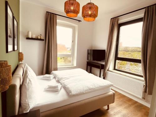 a bedroom with a bed and two windows at Fährhaus Kirschenland in Jork