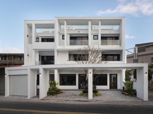 un immeuble d'appartements blanc avec garage dans l'établissement 廷海特潮流民宿 l 近鐵花村 l 自助入住, à Taïtung