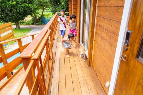 a group of children walking a dog on a porch at 石垣島コテージAkeeesi365 in Ishigaki Island