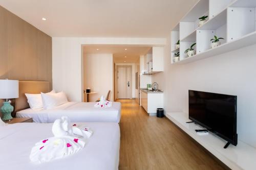two beds in a hotel room with a flat screen tv at The Q Residence Vientiane in Vientiane