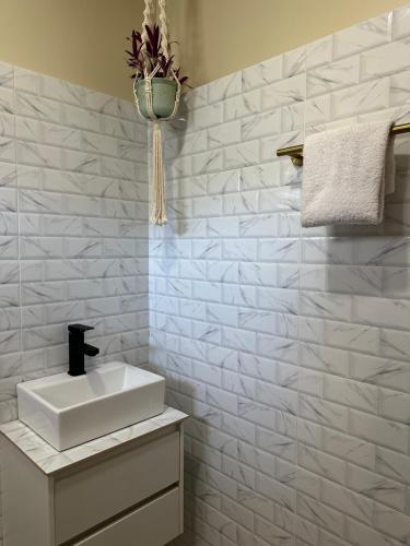 a bathroom with a sink and a white tiled wall at Riverside 2bed cozy apartment in La Trinidad