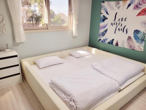 a white bed in a room with a painting on the wall at Stay by J in Jeju