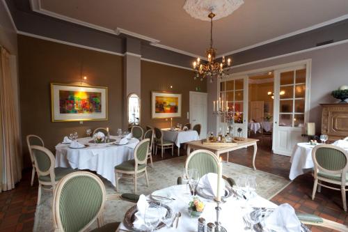 a dining room with tables and chairs and a chandelier at Hotel Schepers in Gronau