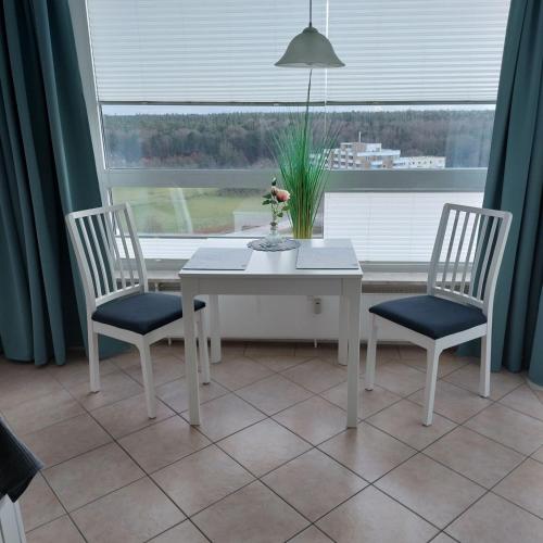 een witte tafel, 2 stoelen en een raam bij Frische Brise 10 OG Nr 5 Meerblick in Cuxhaven