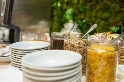 a table topped with white plates and jars of food at Hotel Narenta in Metković