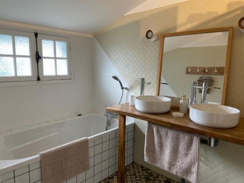 a bathroom with two sinks and a tub and a mirror at Chalet entre océan et foret au calme in Ondres