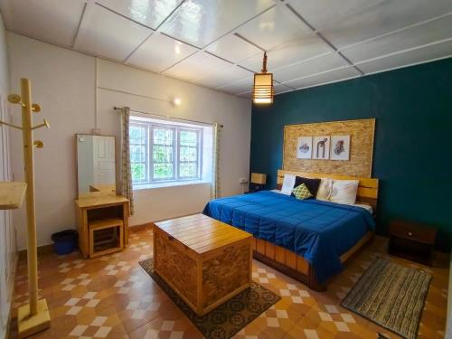 - une chambre avec un lit et un mur bleu dans l'établissement De Huts Kodaikanal, à Kodaikānāl